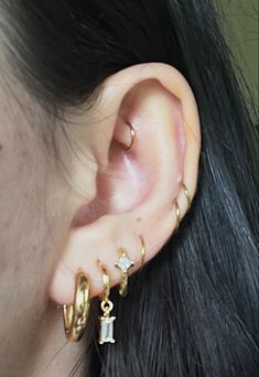 a close up of a person wearing gold ear rings with diamond earrings on their ears