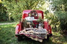 an old red truck with christmas decorations in the back and plaid blanket on the bed