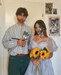 a man and woman standing next to each other in front of a wall with sunflowers