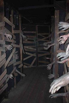 creepy hands reaching out from behind a wooden fence in a dark room with wood slats