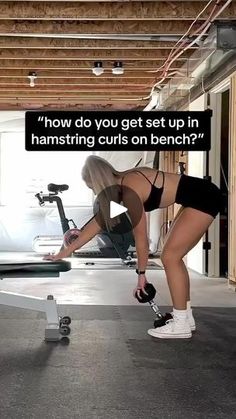 a woman is doing exercises on a stationary exercise bike in a garage with the caption, how do you get set up in hamstring curls on bench?