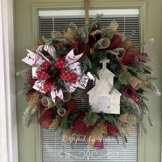 a wreath hanging on the front door with a church ornament attached to it