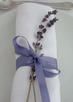 a white plate topped with a purple ribbon and lavender sprig on top of a napkin