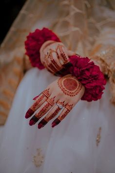 the brides hands are decorated with henna and red flower petals on her wedding day