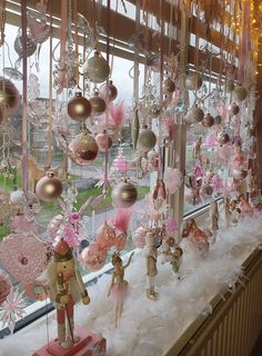 a window display with pink and gold ornaments hanging from it's windowsills