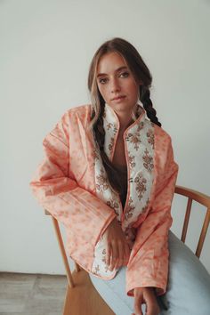 a woman sitting on top of a wooden chair wearing an orange and white pajamasuit