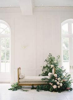 a white room with flowers and greenery on the floor