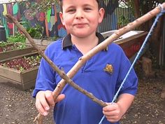 a young boy is holding some branches in his hands