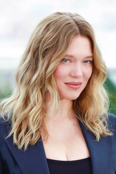 a close up of a person wearing a suit and smiling at the camera with her eyes closed