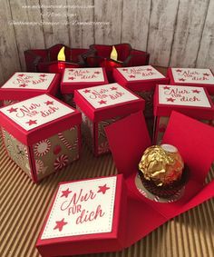 a table topped with lots of red boxes filled with cake and candy covered in gold foil