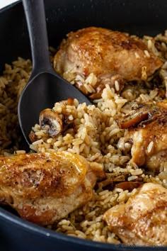 chicken and rice in a skillet with a spoon on the side, ready to be eaten