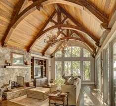 a living room filled with lots of furniture and a fire place under a wooden ceiling