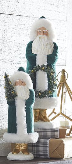 two santa clause statues sitting on top of presents