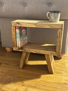 a small wooden table with a book on it next to a couch and coffee cup