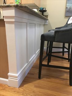 a kitchen island with two stools next to it and a bar in the background