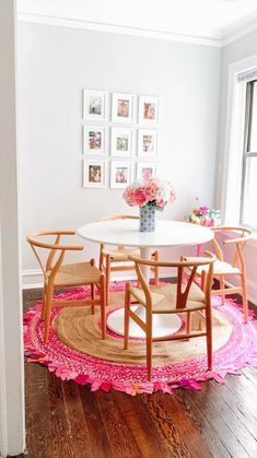 a white table and chairs in a small room with pink rugs on the floor