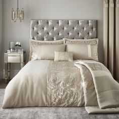 a large bed with beige comforters and pillows