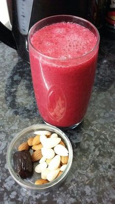 a smoothie and some nuts are on the counter next to a glass of juice