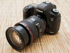 a canon camera sitting on top of a wooden table next to a large lens cup