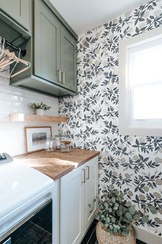 a kitchen with white cabinets and black and white wallpaper, along with a wooden counter top