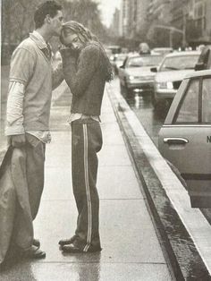 an old photo of two people standing in the rain