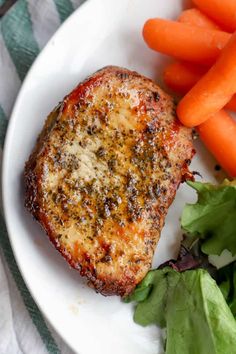 a plate with meat, carrots and lettuce on it