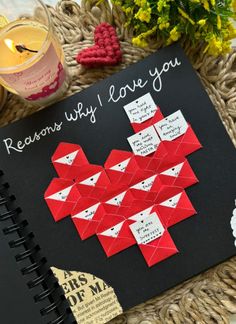 a notebook with some red origami pieces on top of it next to flowers and candles