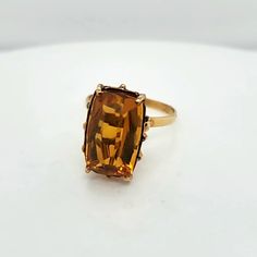 a ring with an orange stone in it on a white surface and gold trimmings