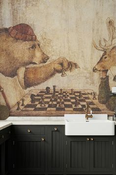 a kitchen with a painting on the wall next to a white sink and black cabinets