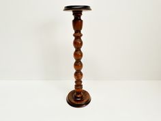 a tall wooden candle holder sitting on top of a white table