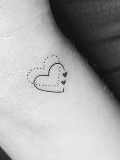 a small heart tattoo on the wrist with dots and hearts drawn on it's side