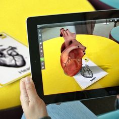 a person is holding up a tablet with an image of a human heart on it