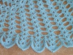 a blue crocheted blanket sitting on top of a wooden floor next to a wall