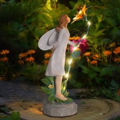 a fairy figurine holding a flower in its hand and lights up the air