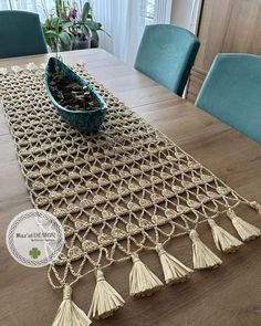 a crocheted table runner with tassels sits on a dining room table