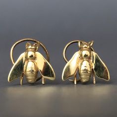 two yellow gold bee cufflinks on grey background