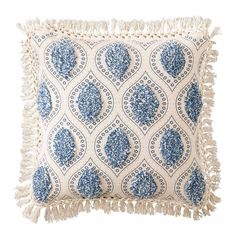 a blue and white pillow with tasselled fringes on the bottom, in front of a white background