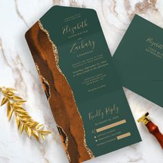 two green and gold wedding programs on a marble table