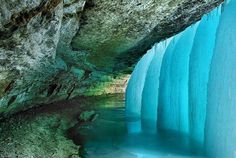 an ice cave with water flowing down it's sides and the walls are blue