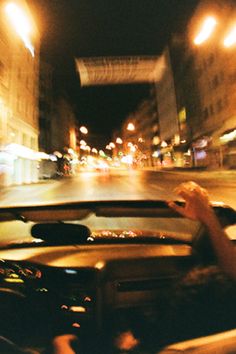 two people in a car driving down the street at night