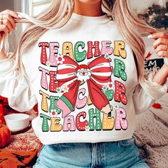 a woman wearing a teacher's t - shirt with a bow on the front