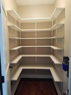 an empty walk in closet with white shelving