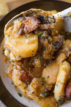 a spoonful of food on a plate with some sort of meat and potato dish