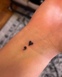 a small black heart tattoo on the wrist