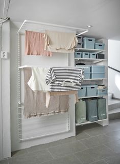 an organized closet with clothes hanging from the ceiling and storage bins on the wall