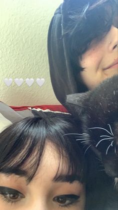 two women with black cats on their heads and one has scissors in her hair, while the other wears cat ears