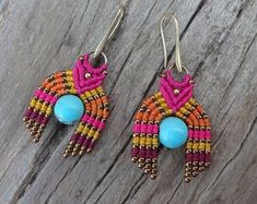 two pairs of colorful beaded bird earrings on wooden table with wood planks in the background