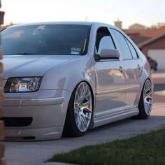 a silver car parked on the side of a road next to a brick wall and grass