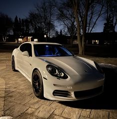 a white sports car parked in the driveway at night