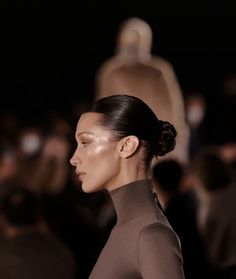 a model walks down the runway in front of a large group of mannequins